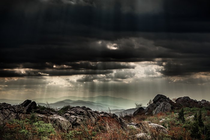 Clima dramático: rayos de luz que descienden sobre las colinas a través de una densa capa de nubes