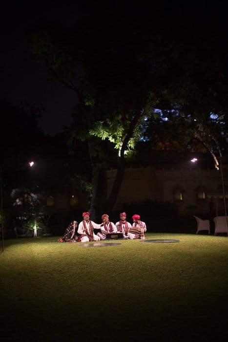Fotografía de viaje de 4 hombres sentados en el césped bajo un árbol por la noche.