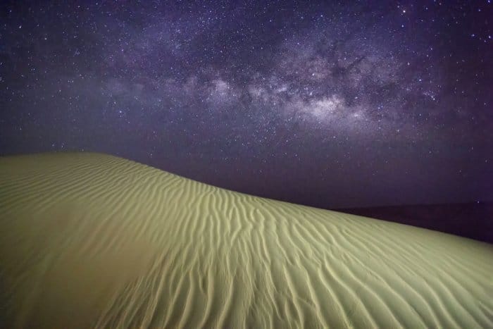 Toma de astrofotografía de un desierto y el cielo nocturno arriba con estrellas y la vía láctea