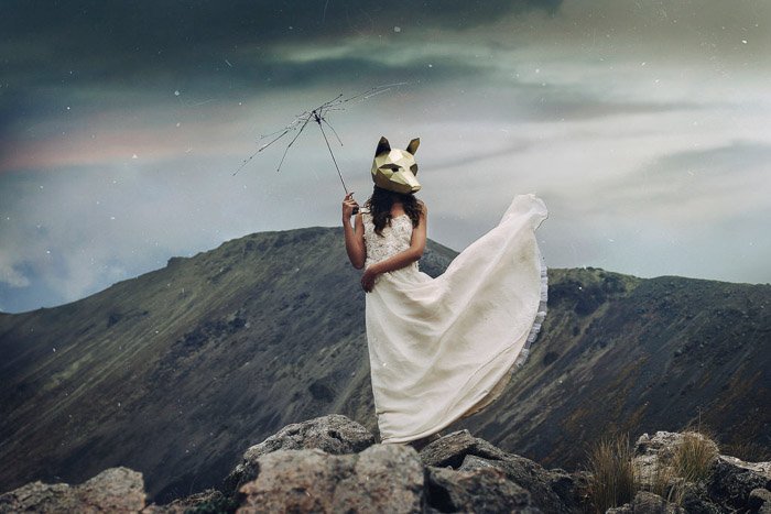 un retrato conceptual de una modelo femenina con una máscara de lobo, de pie en un paisaje montañoso - tipos de fotografía de retrato