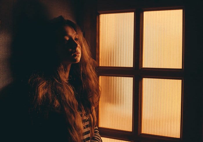 Foto de retrato de una niña junto a una ventana en luz de tungsteno