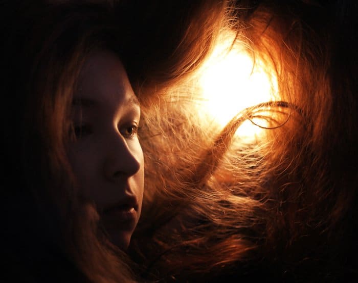 Foto de retrato de una niña con el pelo rojo en luz de tungsteno