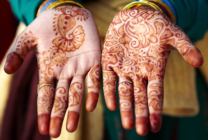 primer plano de manos, palmas hacia arriba, con diseño de henna en ellas