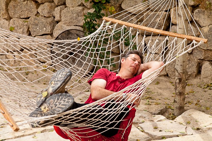 hombre con un pantalones rojo durmiendo en una hamaca al aire libre, un muro de piedra en el fondo - consejos de seguridad de viaje para fotógrafos
