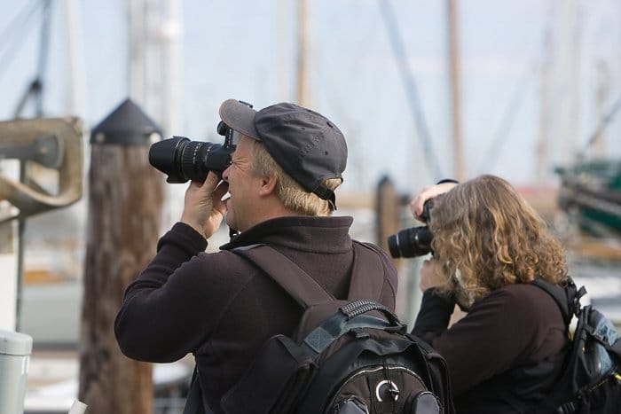 Hombre y mujer en un muelle con DSLR tomando fotos