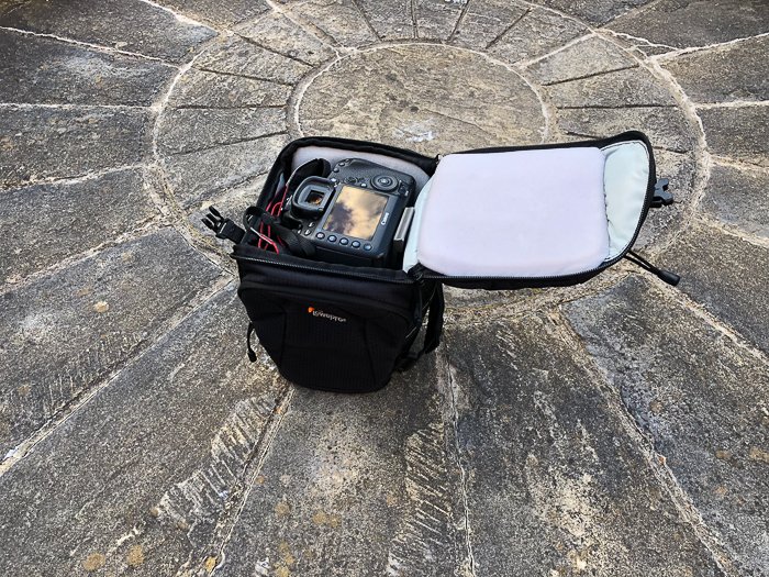 una bolsa de cámara DSLR de carga superior en suelo de piedra