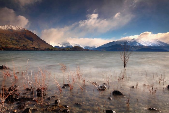 Fotografía de larga exposición del agua en el primer plano de un paisaje montañoso: lista de verificación de fotografía de viajes