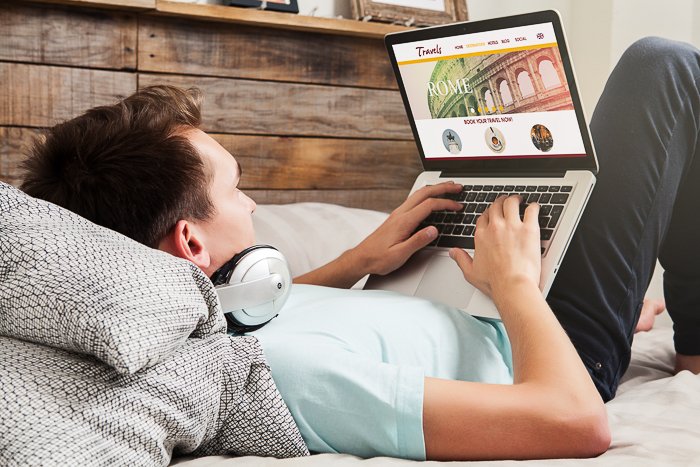 Una foto de un hombre en la cama usando una computadora portátil.