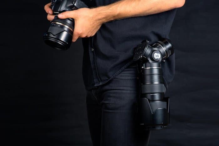 Un fotógrafo sosteniendo una cámara réflex digital con una funda de lente Trilens