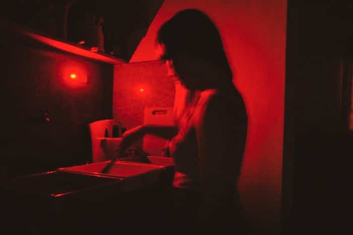 Una persona en un cuarto oscuro de fotografía.