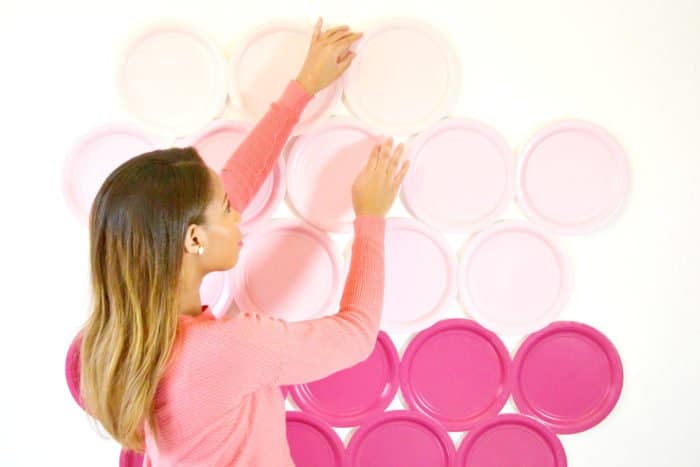 Una persona colgando platos rosas como fondo de fotografía DiY