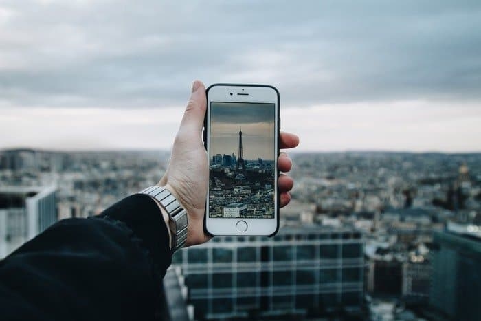 Una persona tomando una foto de la torre Eiffel con un teléfono inteligente