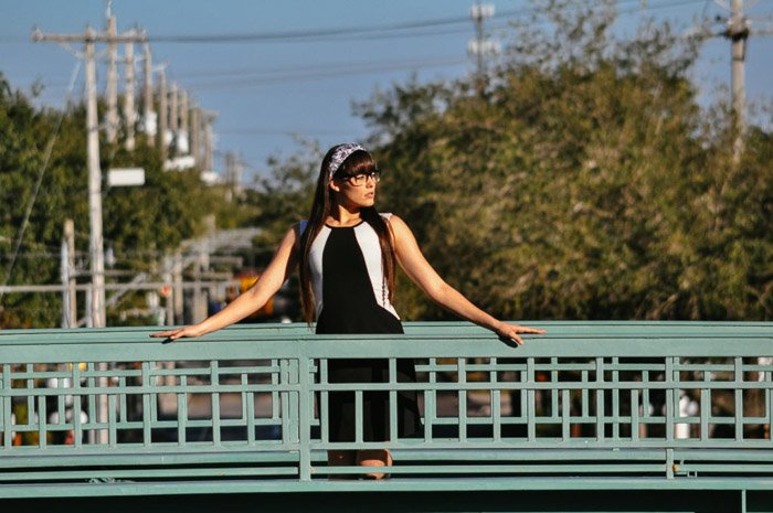 Un retrato de una modelo femenina posando en un puente con un teleobjetivo