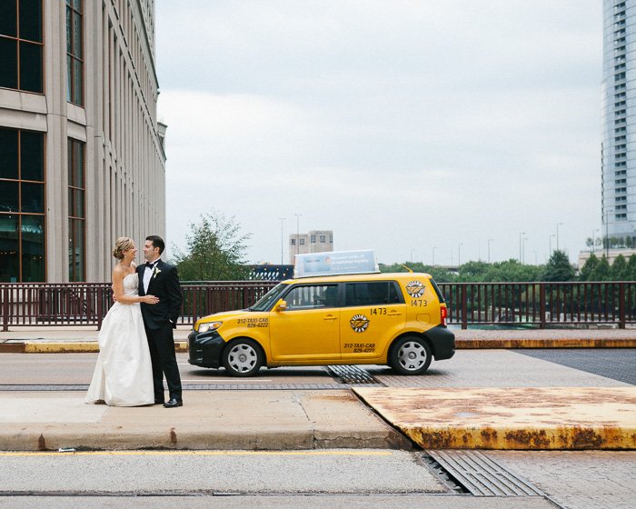 Una pareja de recién casados ​​posando junto al taxi amarillo del centro de Chicago, capturando el momento decisivo en la fotografía