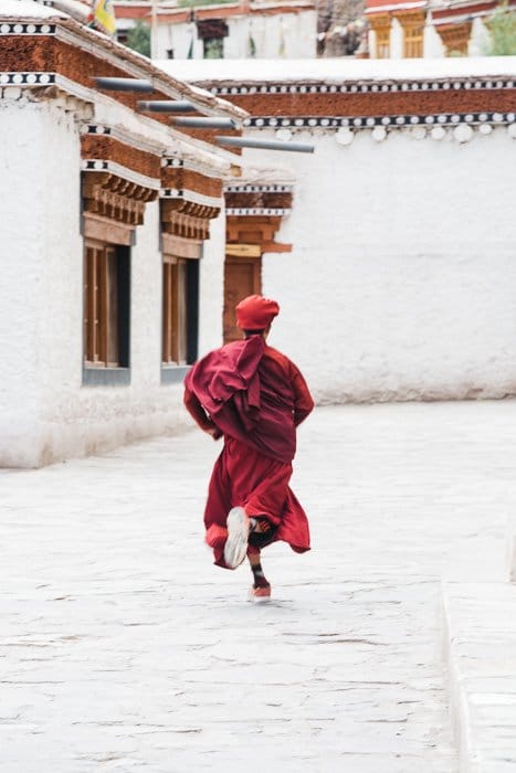 El momento decisivo de un joven monje corriendo por una calle de Ladakh