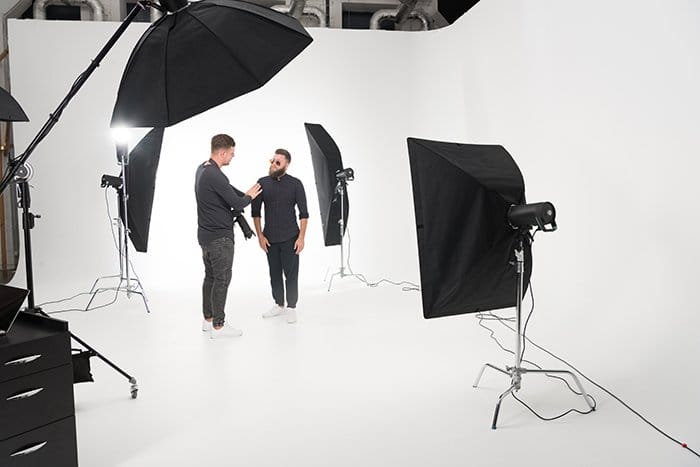Dos hombres de pie en un estudio fotográfico con luces estroboscópicas.