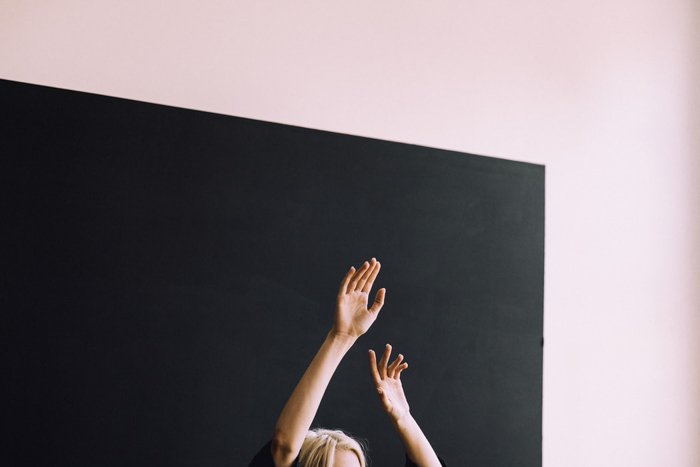 Una mujer posando con las manos en el aire.