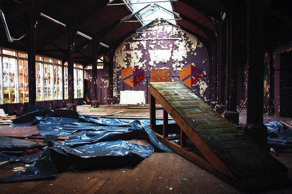 Salón de un internado abandonado con paredes en ruinas y luz natural que entra desde la parte superior