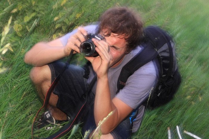 Un retrato borroso de un fotógrafo disparando con una DSLR al aire libre