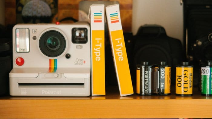 Una imagen de una cámara instantánea Polaroid y películas instantáneas además de rollos de película de 35 m rollos de película