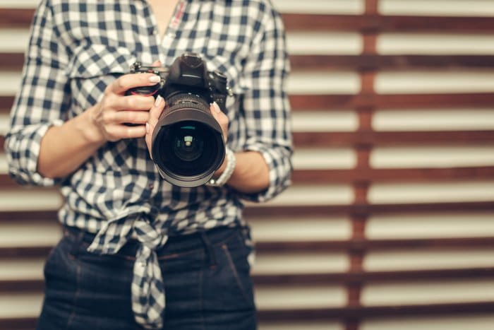 Foto de una mujer sosteniendo una cámara réflex digital en su mano