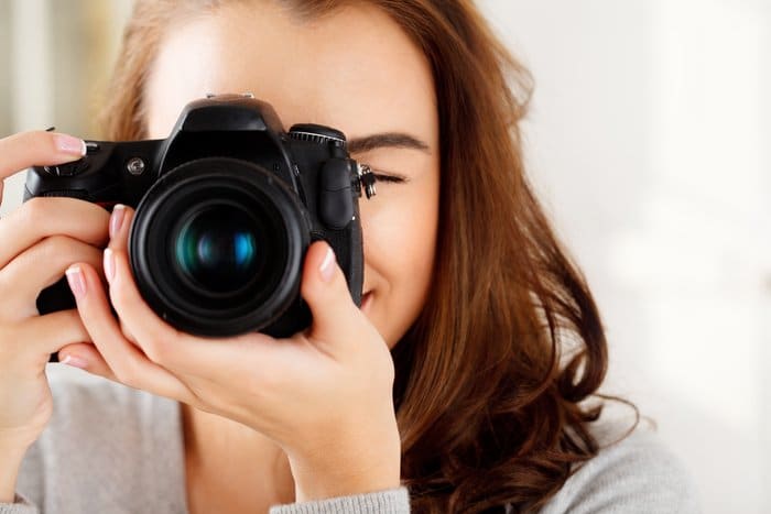 Foto de primer plano de una mujer tomando una foto con una cámara réflex digital