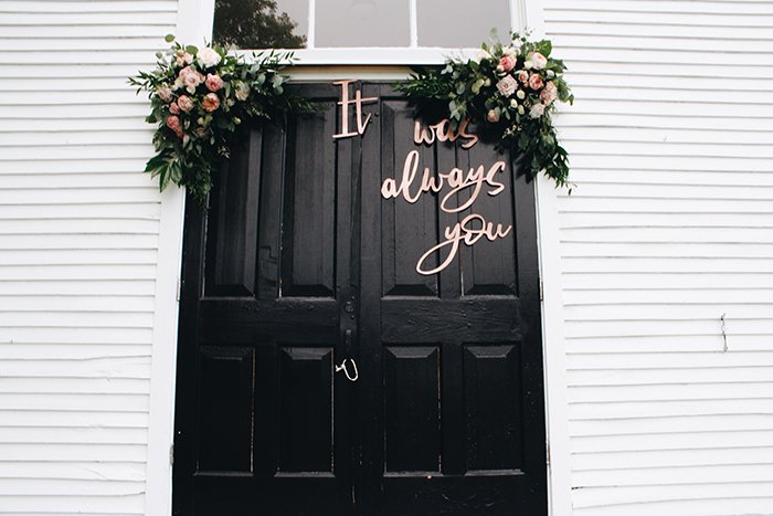 una puerta decorada con flores y letras como accesorios de fotografía de bodas