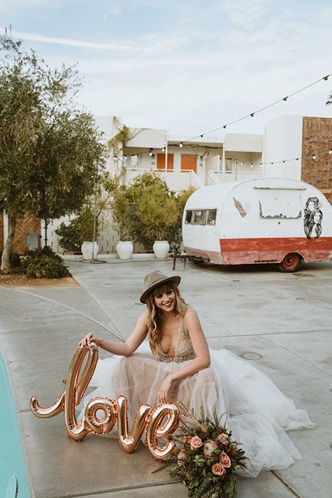 Una novia posando con flores y globos.