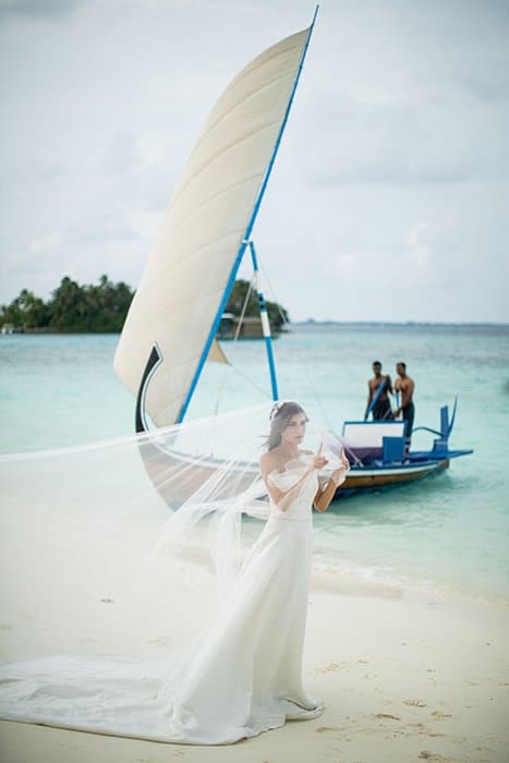 Una novia posando con un barco en el fondo.