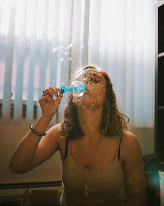 Un retrato de un modelo femenino soplando burbujas filmado con un disparador de flash inalámbrico