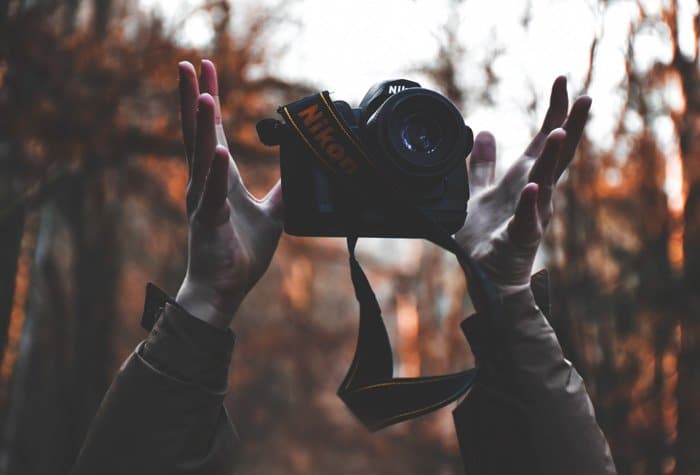 Un fotógrafo lanzando juguetonamente su cámara Nikon DSLR al aire