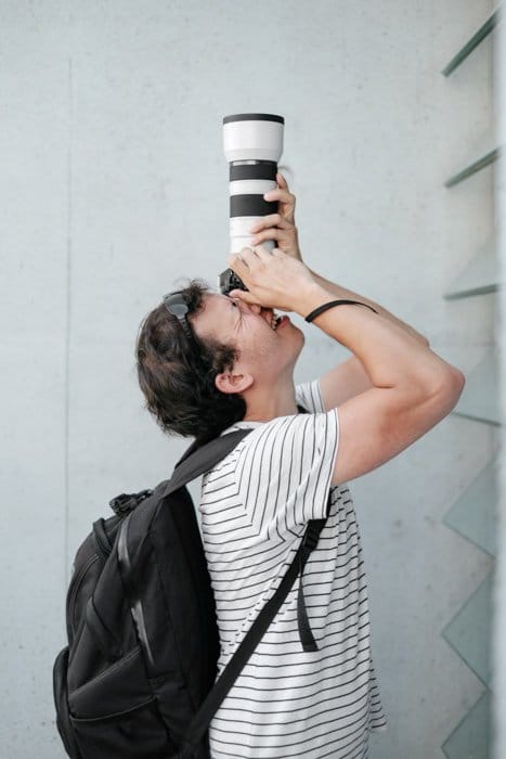 Un fotógrafo disparando a través de una cámara DSLR con un teleconvertidor