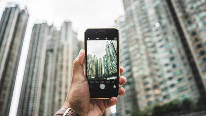 Una persona tomando una foto de rascacielos con un teléfono inteligente