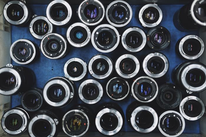 Fotografía aérea de una gama de lentes para fotografía de bodas sobre fondo azul.