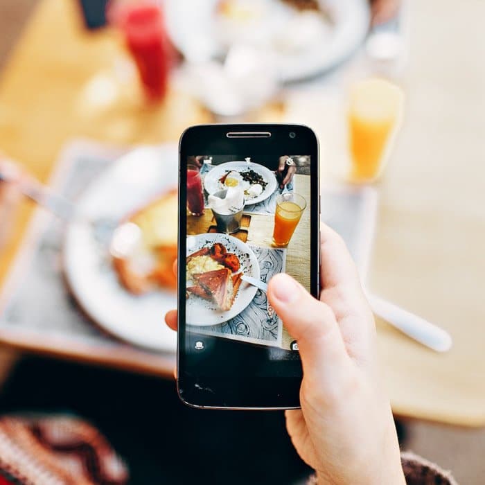 Una persona que toma una fotografía de comida con un teléfono inteligente.