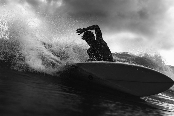 Imagen en blanco y negro de un hombre con una tabla de surf en las olas