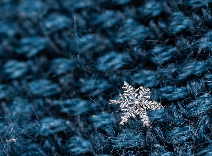 Un pequeño copo de nieve descansando sobre lana azul