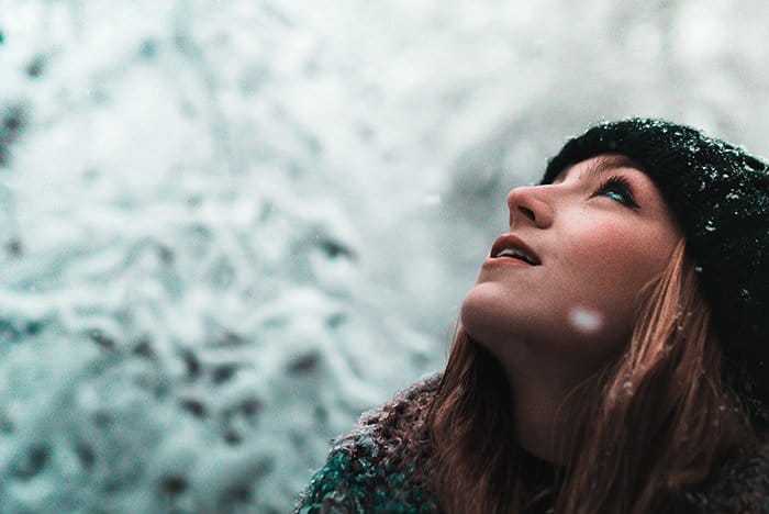 Cerrar fotografía de retrato de invierno de un modelo femenino posando en la nieve que cae