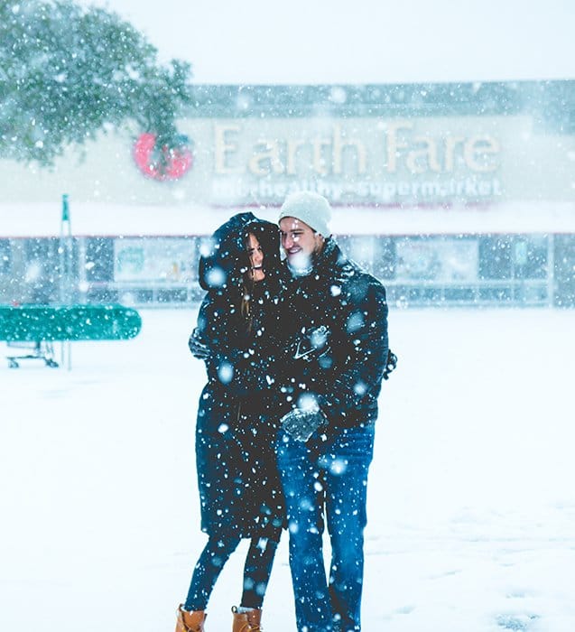 Cerrar fotografía de retrato de invierno de una pareja posando en la nieve que cae