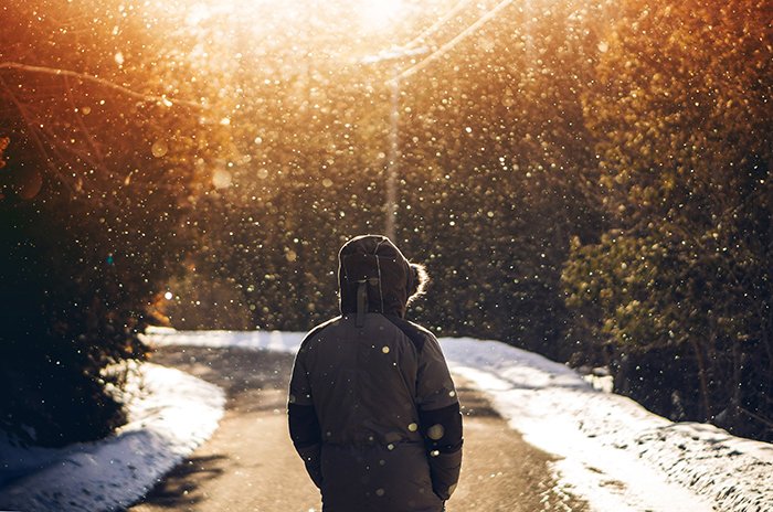 Atmospher retrato de invierno de un modelo caminando por una carretera bajo la nieve que cae