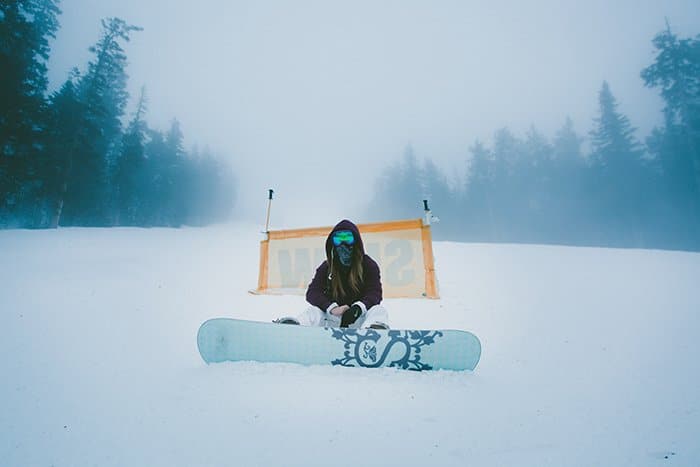 Retratos de nieve atmosférica de una mujer snowboarder posando en un paisaje invernal