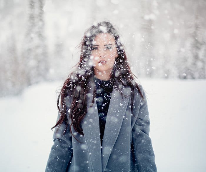 Fotografía de retrato de invierno mágico de una modelo femenina posando en la nieve que cae