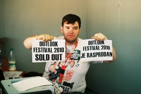 Foto de un hombre con dos carteles de "Festival agotado" filmada