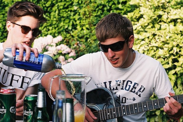 Foto de un chico sirviendo una bebida y otro tocando una guitarra filmada