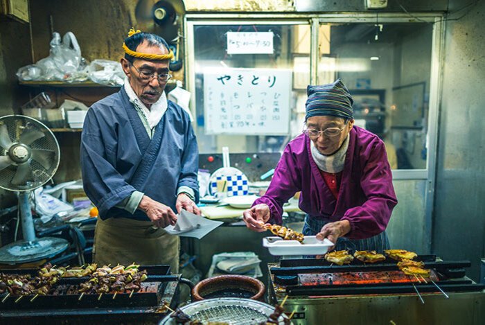 Fotografía de personas en un puesto de comida en un mercado asiático tomada con una lente gran angular
