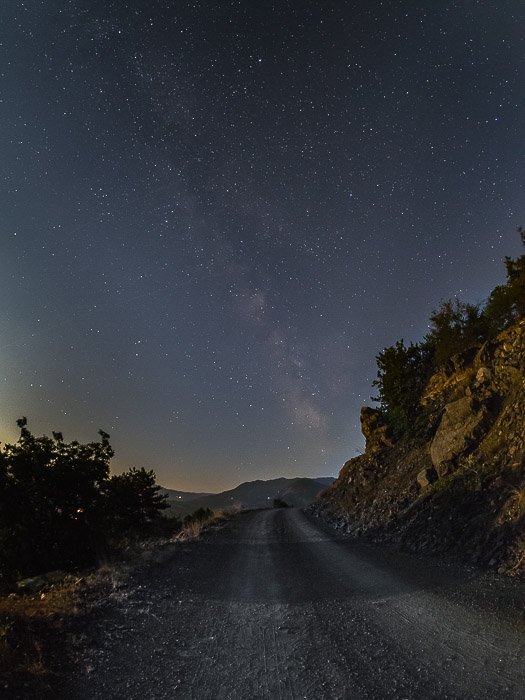 Un camino rural por la noche bajo un cielo lleno de estrellas