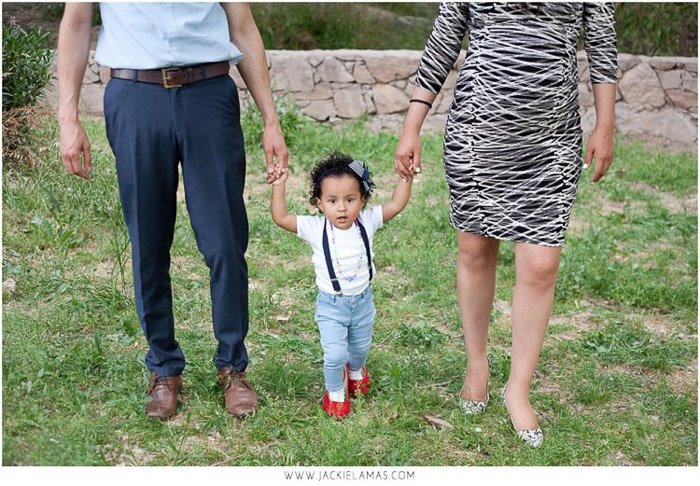 dulce retrato familiar de padres sosteniendo la mano de una niña al aire libre