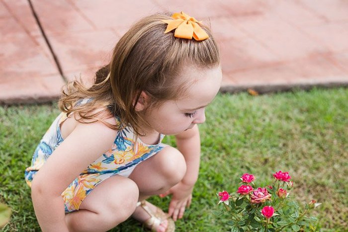 retrato de estilo de vida de una niña agachada en la hierba