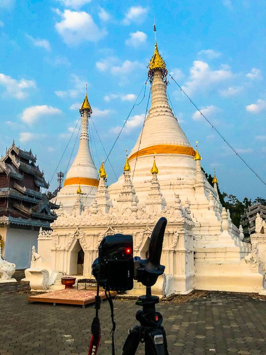 Cámara sobre trípode listo para fotografiar la estupa budista contra un cielo azul brillante temprano en la mañana