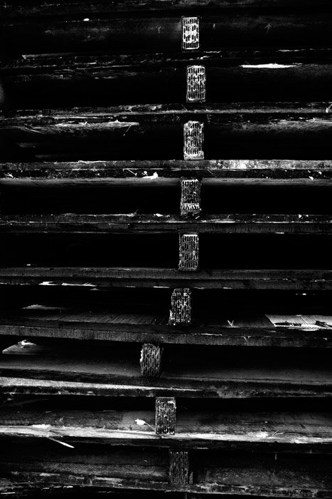 Una oscura fotografía en blanco y negro de una pila de paletas de madera.